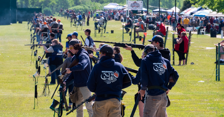 A group of people standing in a field with rifles.